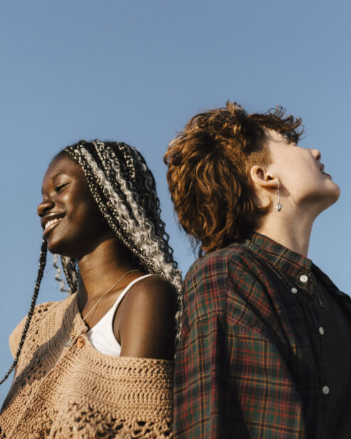 Two people smiling in front of a blue sky